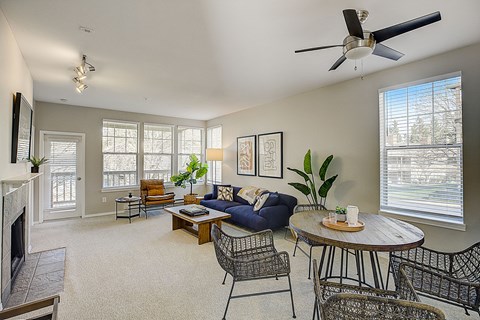 a living room with a blue couch and a round table and a ceiling fan